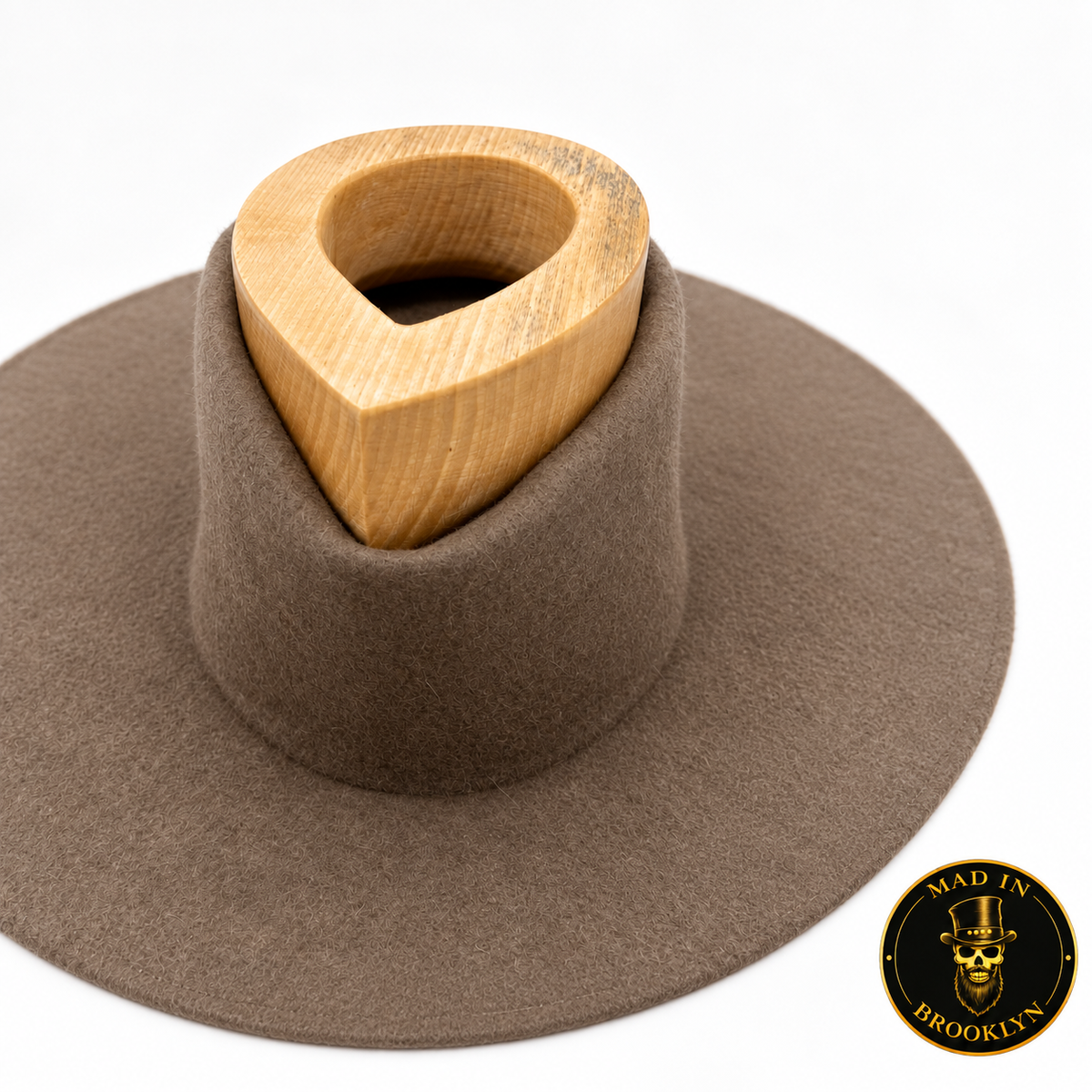 Wooden teardrop shaping tool demonstrated on a felt hat crown